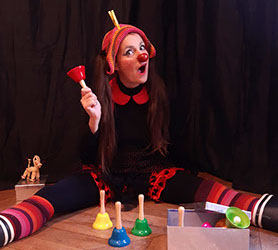 Photo. Le clown, Mlle Slurp, s'amuse avec des cloches de toutes les couleurs.