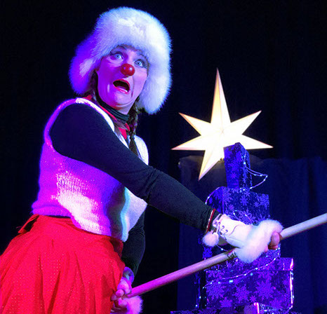 Le clown fait une grimaçe avec un balai entre les jambes