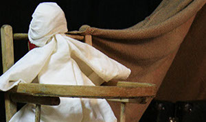 Photo d'un poupon en chiffon assis dans une chaise pour enfant.