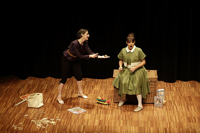 Photo spectacle. Une femme présente un petit jouet à une autre, qui semble outrée.